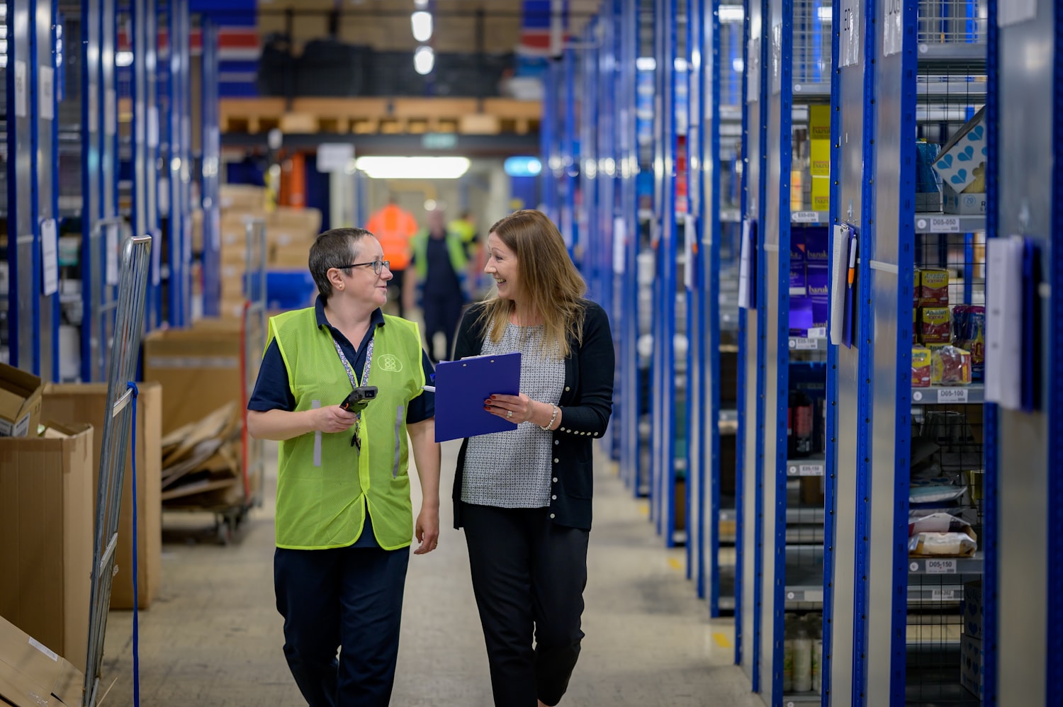 Two people walking a warehouse aisle, checking inventory together